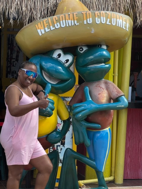 Freddie smiling beside the Welcome to Cozumel frog statues