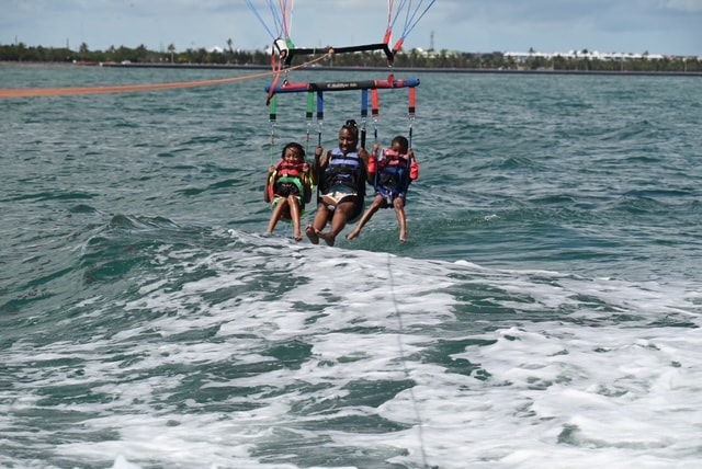 Freddie and two children parasailing over ocean waves