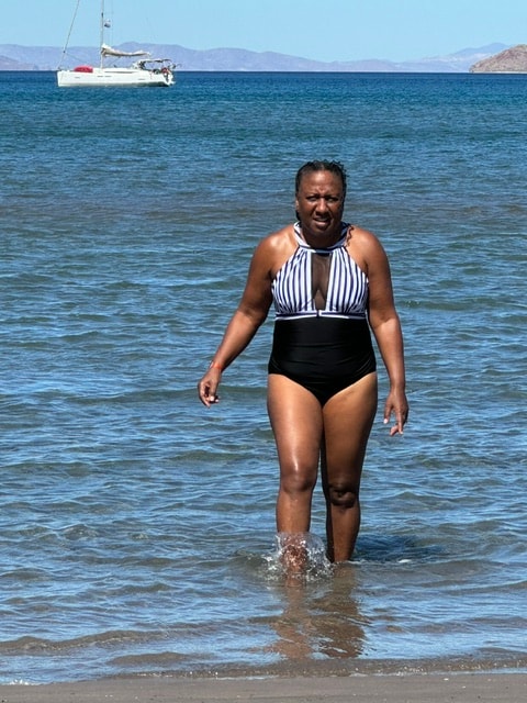 Freddie wading into the sea with a sailboat in the background