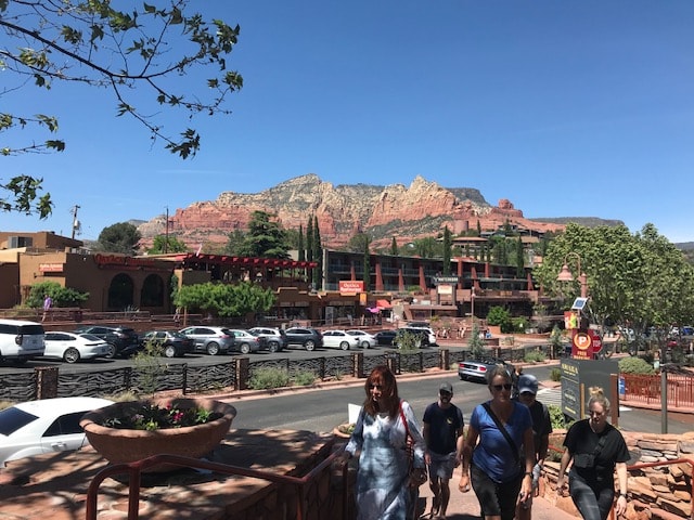 A Sedona street scene with red rock mountains rising behind the shops